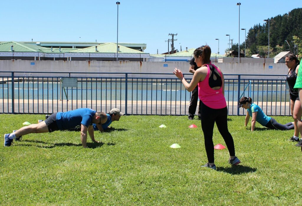 A group exercising on grass during an outdoor fitness session