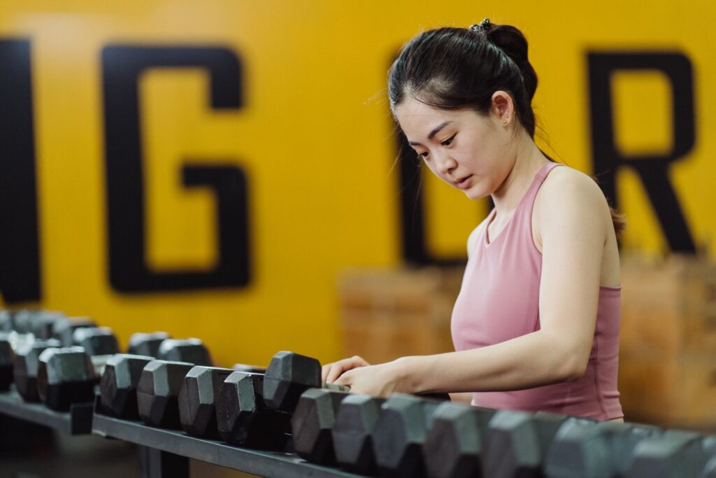 Woman selecting a dumbbell from a gym rack before strength training